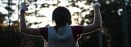 A girl in the sunlight, with sand falling through her hands.